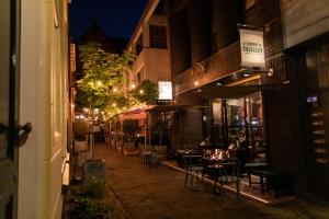 uma rua vazia à noite com mesas e cadeiras em Hotel The Happy Traveler em Groningen