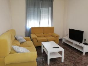 a living room with a yellow couch and a tv at Apartamentos Buendia in Buendía