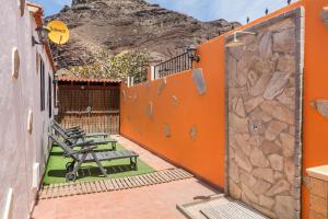 een patio met banken en een berg op de achtergrond bij Casa costera playa de Tasarte in San Nicolás