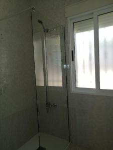 a shower with a glass door and a window at Apartamentos Buendia in Buendía