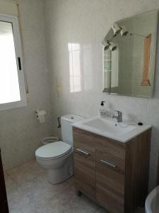 bagno con servizi igienici, lavandino e specchio di Apartamentos Buendia a Buendía