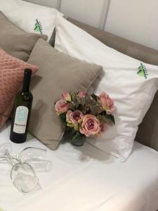 a bottle of wine and a bouquet of flowers on a bed at Danijela & konak in Zlatibor