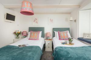 two beds in a room with green and pink at Mariners Cottage, St Ives in St Ives