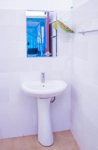 uma casa de banho com um lavatório branco e um espelho. em Royal Wonders Hotel em Moshi