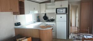 a kitchen with white cabinets and a white refrigerator at cottage Tangro in Middelkerke