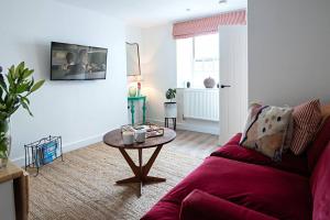 uma sala de estar com um sofá vermelho e uma mesa em The Courtyard Apartment with parking em Ilfracombe