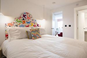 um quarto com uma cama branca e uma cabeceira colorida em The Courtyard Apartment with parking em Ilfracombe