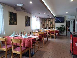 uma sala de jantar com mesas e cadeiras e uma televisão em Guesthouse Živko em Dobrovce