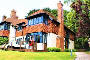 a large brick house with blue windows on a lawn at Stylish Seaview House with Hot Tub in Hythe