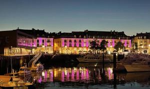 un bâtiment éclairé avec des lumières violettes dans un port dans l'établissement Studio Saint Rémy Dieppe, à Dieppe