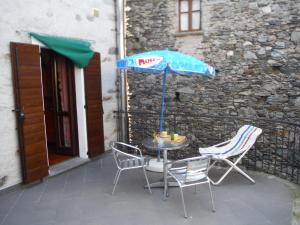 una mesa con sillas y una sombrilla en el patio en Gravedona Village House, en Gravedona