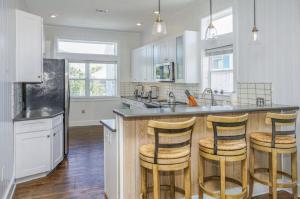 a kitchen with white cabinets and a island with bar stools at Sea Prize at Grayton Beach in Santa Rosa Beach