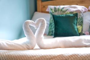 two towels shaped like swans sitting on a bed at Charming 4 Bedroom House in Prime Location - Close to City Centre - Free Parking, Smart TVs and Landscaped Garden by Yoko Property in Milton Keynes