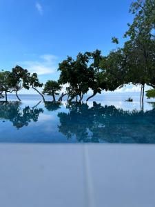 a painting of trees in the water with a blue sky at SABAI Beach in Baru