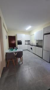 a kitchen with white cabinets and a table and chairs at Central Two Bedroom Apartment, No 101, by IMH Travel & Tours in Paphos