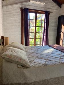1 dormitorio con 1 cama grande y ventana en Los Nidos, en Piriápolis