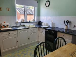 a kitchen with white cabinets and black counter tops at Ash Cottage in Stranraer
