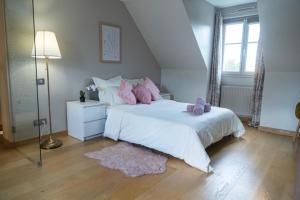 - une chambre avec un grand lit blanc et des oreillers roses dans l'établissement Belle Demeure en bord de Seine, à Villeneuve-la-Garenne