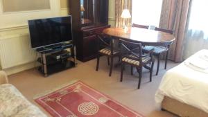 a living room with a television and a table and chairs at Holidayaparthotel 4 in London