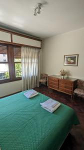 1 dormitorio con 1 cama verde y 2 toallas en Espejo Senior en Mendoza