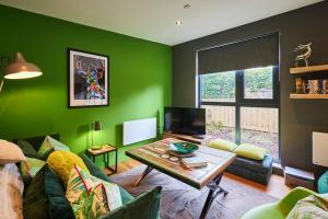 Sala de estar verde con sofá y mesa en Host & Stay - Forest Green Lodge, en Alnwick