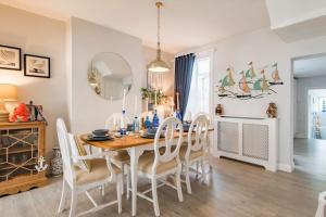 a dining room with a wooden table and chairs at Driftwood - Charming family home in Deal