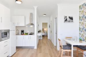 una cucina con mobili bianchi e un tavolo da pranzo di Maranuelas Beachfront 305 FP by VillaGranCanaria a Arguineguín