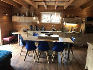 uma cozinha com uma grande mesa de madeira e cadeiras azuis em Obere-Seeterrasse em Rieden