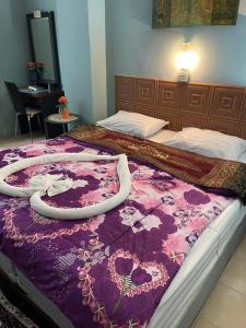 a bed with a purple blanket on top of it at San Antonio Beach Guesthouse & Restaurant in Kata Beach