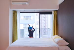 a child is standing in front of a bedroom window at Rest Kujo Apartment in Osaka