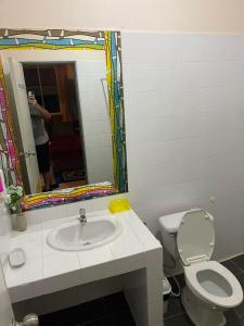 a bathroom with a toilet and a sink and a mirror at San Antonio Beach Guesthouse & Restaurant in Kata Beach