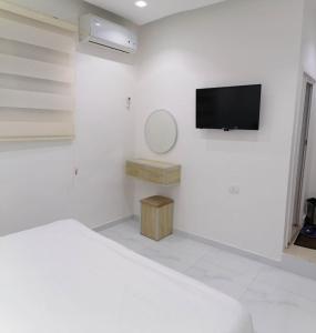 a white bedroom with a bed and a tv on a wall at Mussa Spring Hotel in Wadi Musa