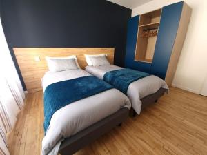 two beds in a room with blue walls and wooden floors at Spacieux au cœur de Pont-Aven Au Bois d'Amour 1-6p in Pont-Aven