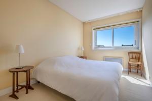 een slaapkamer met een wit bed en een raam bij Face au port, appartement pour 4 personnes in Le Pouliguen