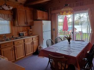 a kitchen with a table and a refrigerator at Augur Lake Cabin Escape in Au Sable Forks