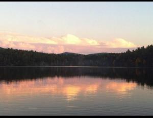 un lac avec le soleil réfléchissant sur l'eau dans l'établissement Augur Lake Cabin Escape, à Au Sable Forks