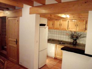 eine Küche mit einem weißen Kühlschrank und Holzschränken in der Unterkunft Gîte La Grange logement de qualité in Cauterets