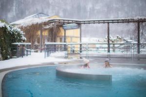 two children playing in a swimming pool in the snow at Gîte La Grange logement de qualité in Cauterets