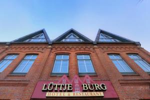 un edificio de ladrillo rojo con un letrero de neón. en Hotel Lüttje Burg en Lütjenburg