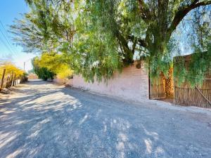 un camino vacío con un árbol y una valla en Cabañas Turi Lackar en San Pedro de Atacama