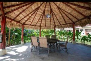 a patio with a table and chairs under a straw umbrella at Cabo Velas 19 Jungle Paradise in Santa Cruz