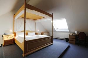 ein Schlafzimmer mit einem Himmelbett und einem Schreibtisch in der Unterkunft Hotel Lüttje Burg in Lütjenburg