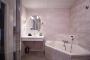 a bathroom with a tub and a sink and a bath tub at Grand Hotel en Résidence De Draak in Bergen op Zoom