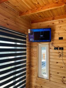 TV en la pared de una cabaña de madera con ventana en Cabañas Santa Elena en Pelluhue