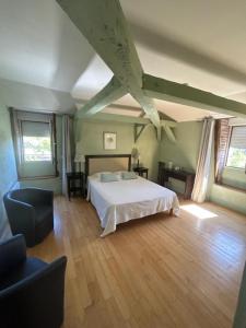 Schlafzimmer mit einem weißen Bett und Holzboden in der Unterkunft Maison Redon chambres d'hôtes in Tour-de-Faure