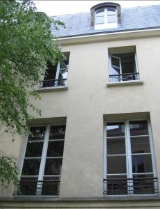 ein weißes Gebäude mit drei Fenstern und einem Dach in der Unterkunft La Clé d'Anne in Saint-Germain-en-Laye