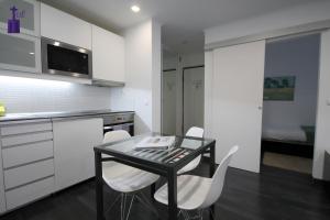 uma cozinha com uma mesa preta e cadeiras brancas em Lisbon North Apartment em Lisboa