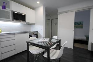 cocina con mesa negra y sillas blancas en Lisbon North Apartment, en Lisboa