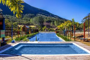 uma grande piscina com uma montanha ao fundo em Art Green Teresópolis em Teresópolis
