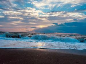 a beach with crashing waves and a cloudy sky at Excelsior apartaments 2 mamaia nord in Mamaia Nord